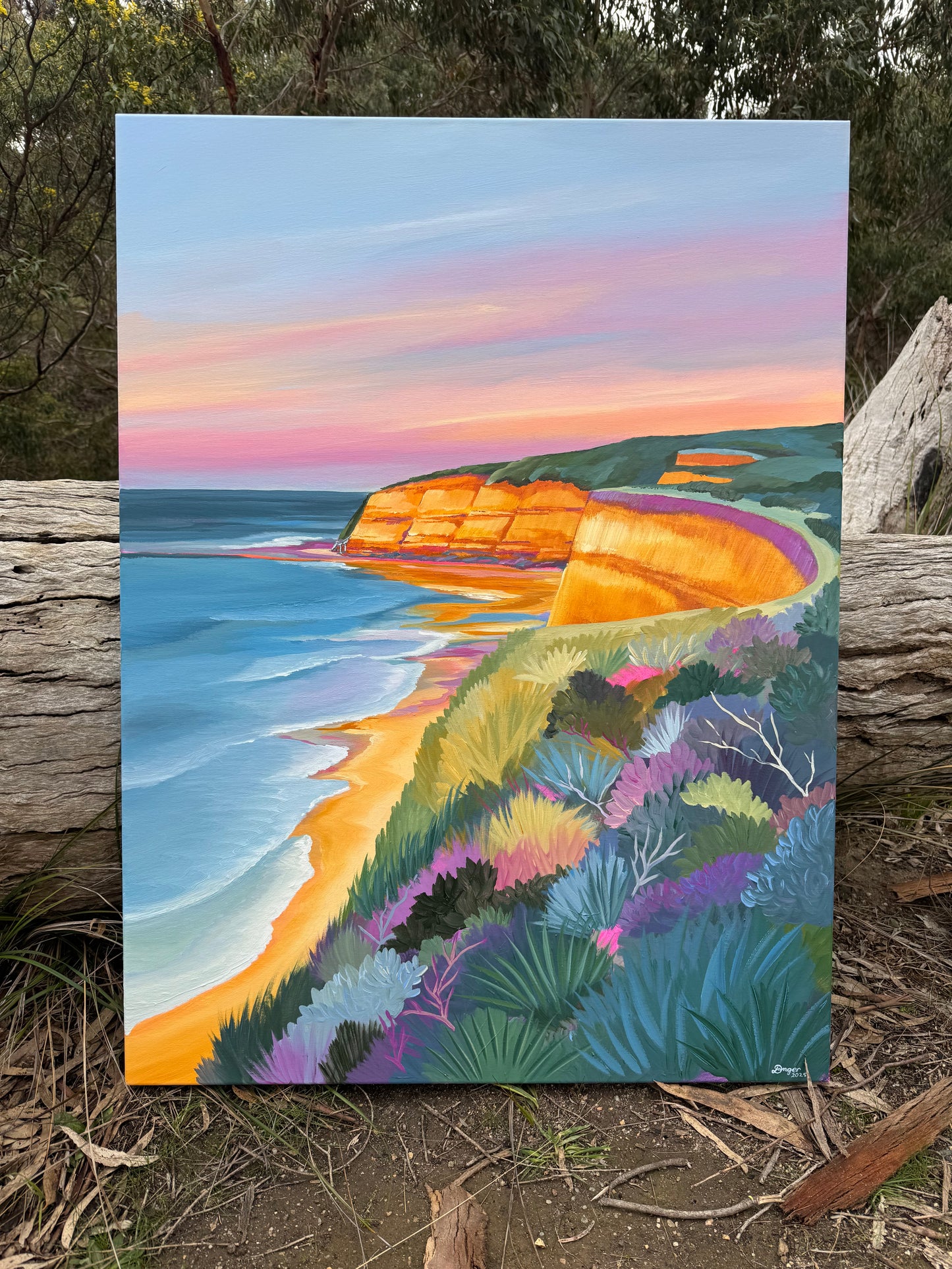 Jan Juc at sunrise, a colourful seascape original painting inspired by the Surf Coast location of Jan Juc near Torquay, Victoria, Australia. Painting is sitting in a bush setting for scale.