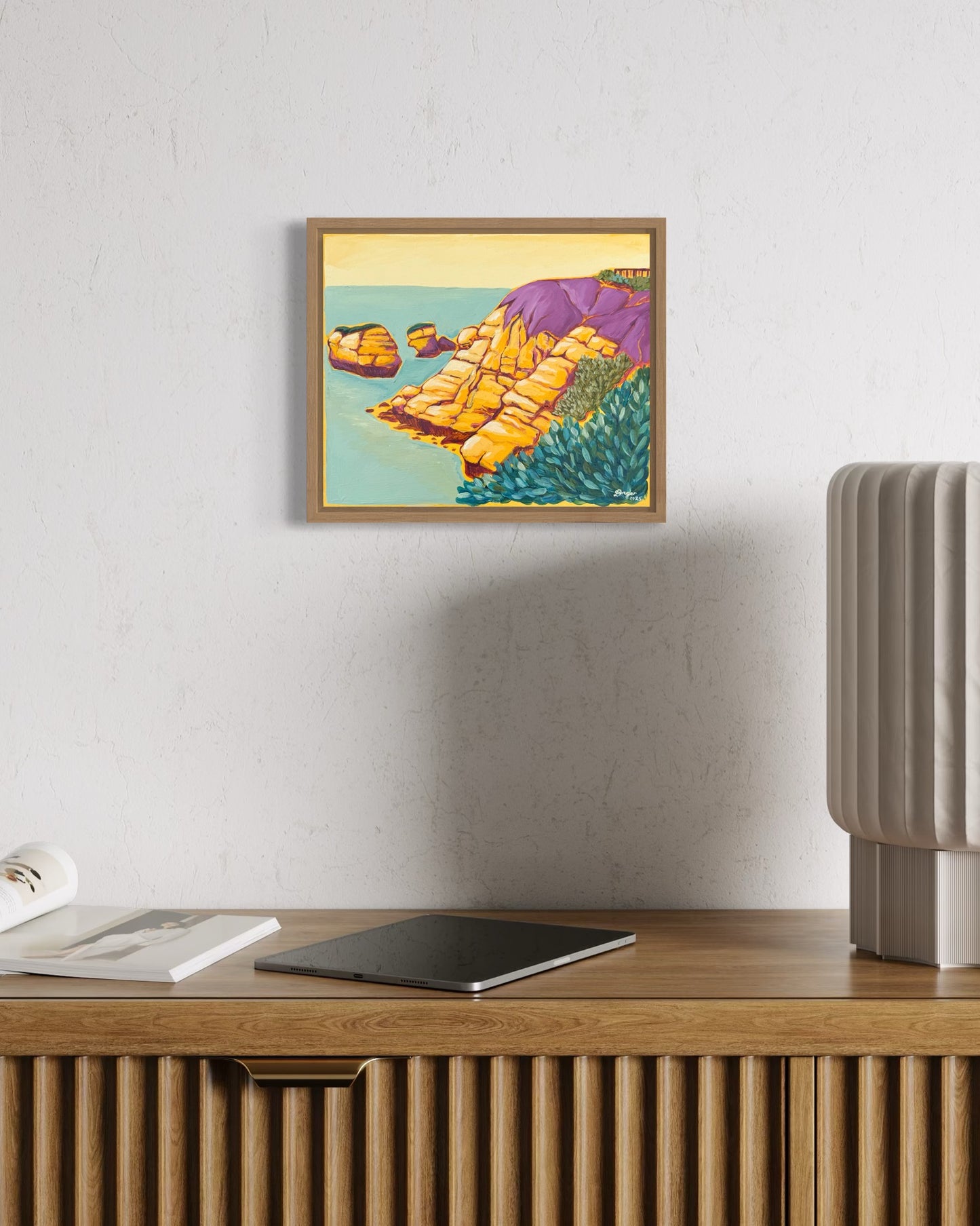 Torquay - Rocky Point in Yellow artwork framed in raw oak, mixed media on board created by artist Lauren Danger. Artwork displayed on a white wall above an oak sideboard in a living room.