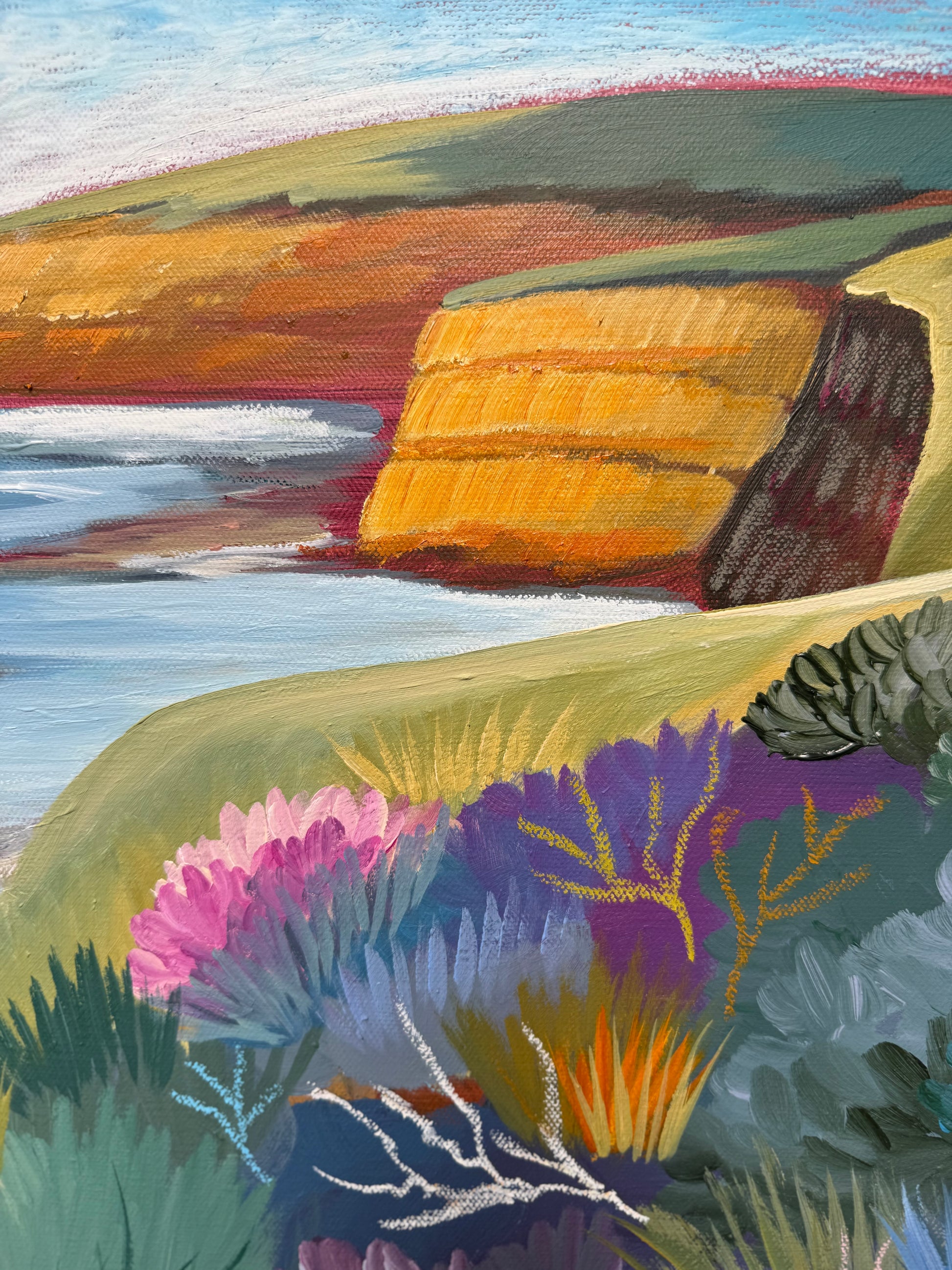 A close up of the colourful artwork Jan Juc at Day by Lauren Danger.  The image has vibrant colours of the cliffs sea and vegetation in Jan Juc in acrylic and pastel.