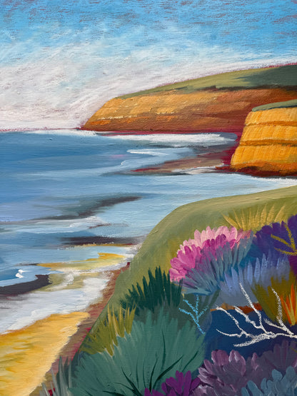 A close up of the colourful artwork Jan Juc at Day by Lauren Danger.  The image has vibrant colours of the  vegetation, ocean and cliffs in Jan Juc in acrylic and pastel.