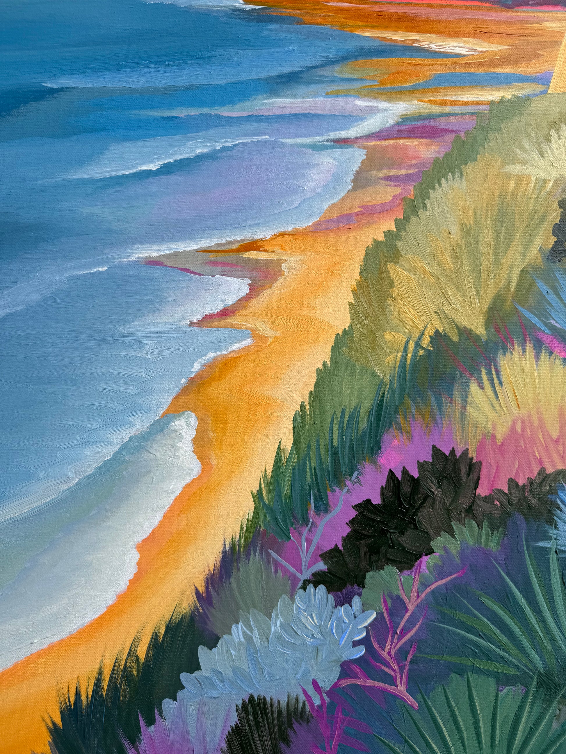 A colourful close up of the original painting of Jan Juc at Sunrise.  Image has shrubs, trees and grass of the coastline in a range of bright colours as well as ocean blues in the water and bright orange sand.