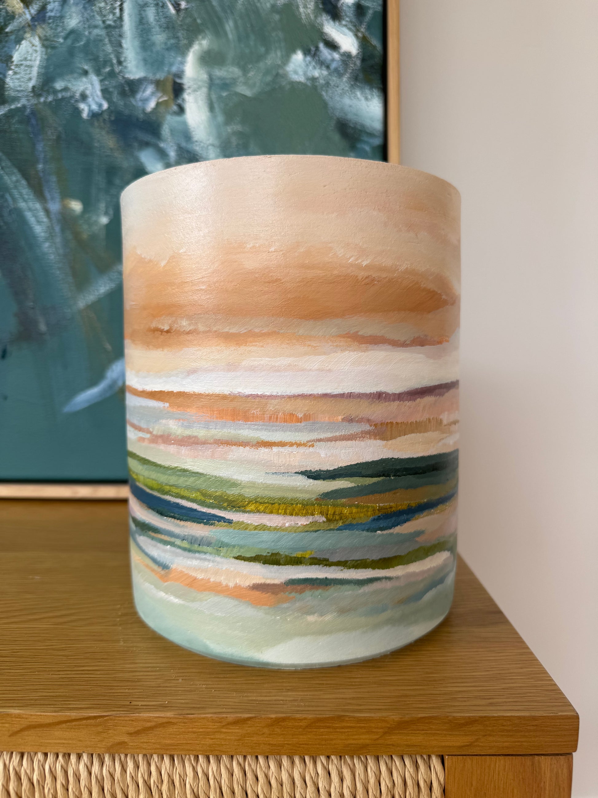 Closer view of a hand-painted ceramic vase with pastel coastal landscape, displayed on timber sideboard 